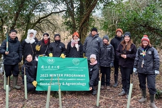 A group of students outdoors, holding a banner reading "2025 Winter Programme, Sustainability and Agroecology", "Cambridgeshire Cultural Exchange Centre"