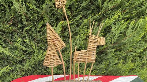 Willow centrepiece made of a weaved reindeer, christmas trees and a star attached to a log