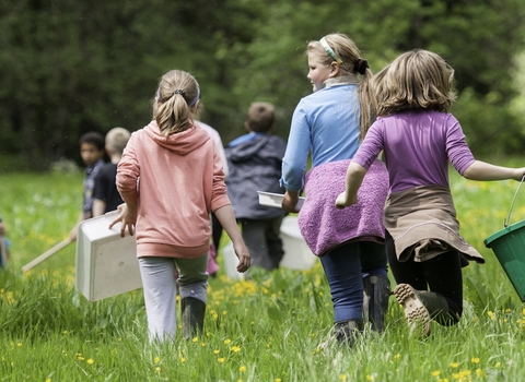 children walking away across a meadow